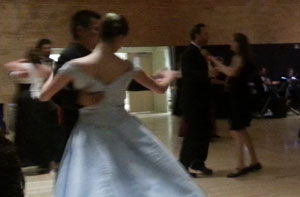 Photo of well-dressed dancers watching as the Waltzers swirl around the dance floor